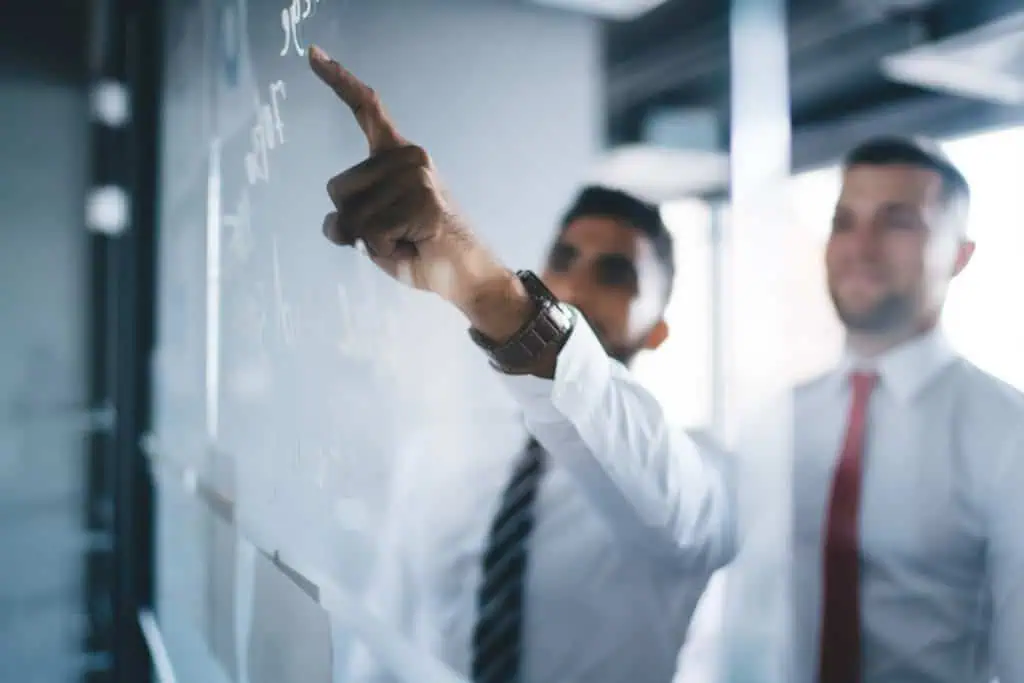 two men looking at glass board with one pointing