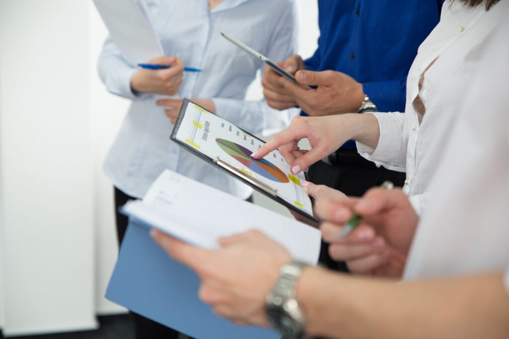Office workers gathered with one pointing at the chart in their hand