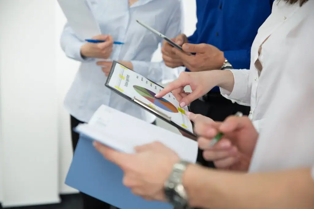 Office workers gathered with one pointing at the chart in their hand
