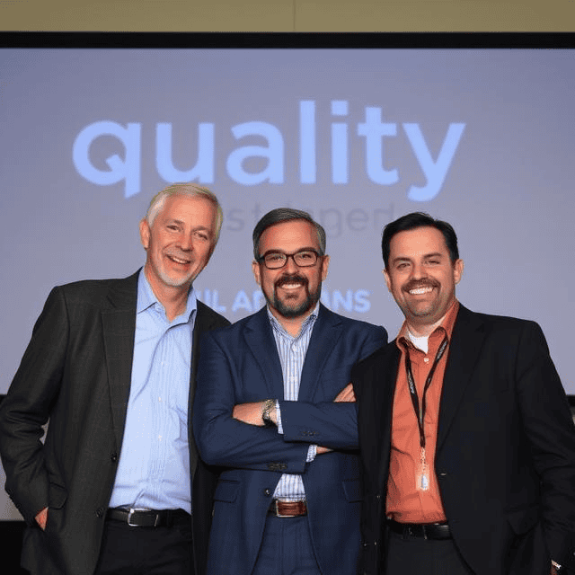 Three quality managers in suits standing next to each other smiling