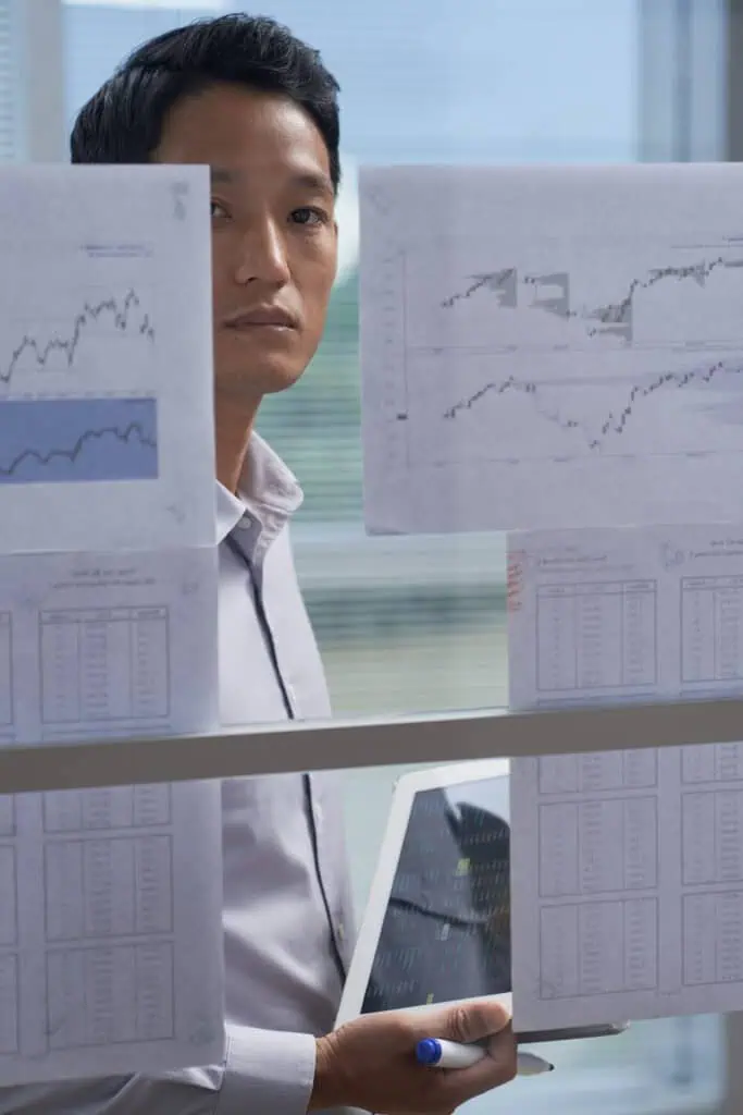 Young man working in financial department with reports sticked on glass in office