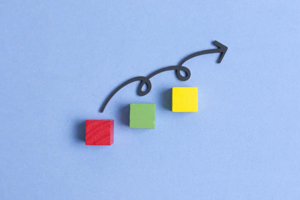 Curvy line jumping on three colourful cubes symbollizing continuous improvement