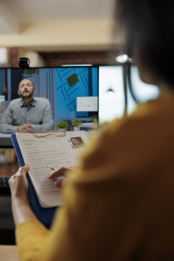 Businesswoman analyzing candidate CV discussing hiring with a man during online videocall meeting.