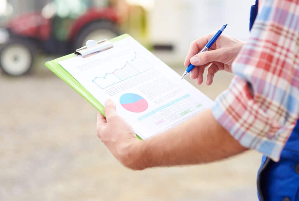 A person holding a clipboard with a pen and graph