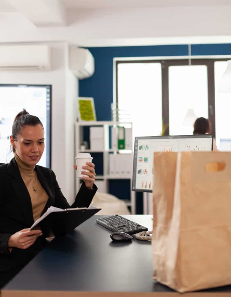 Sourcing services expert sitting at her desk with a cofee in her hand, studying report file