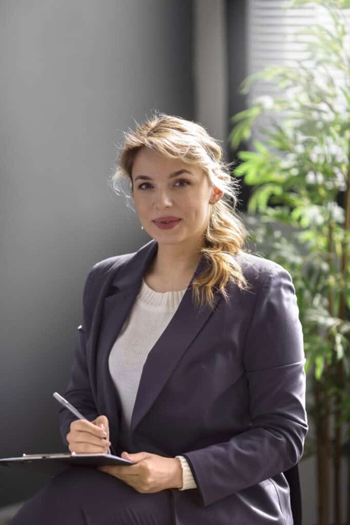 HR interim manager sits in office paying attention while takng notes with her pen