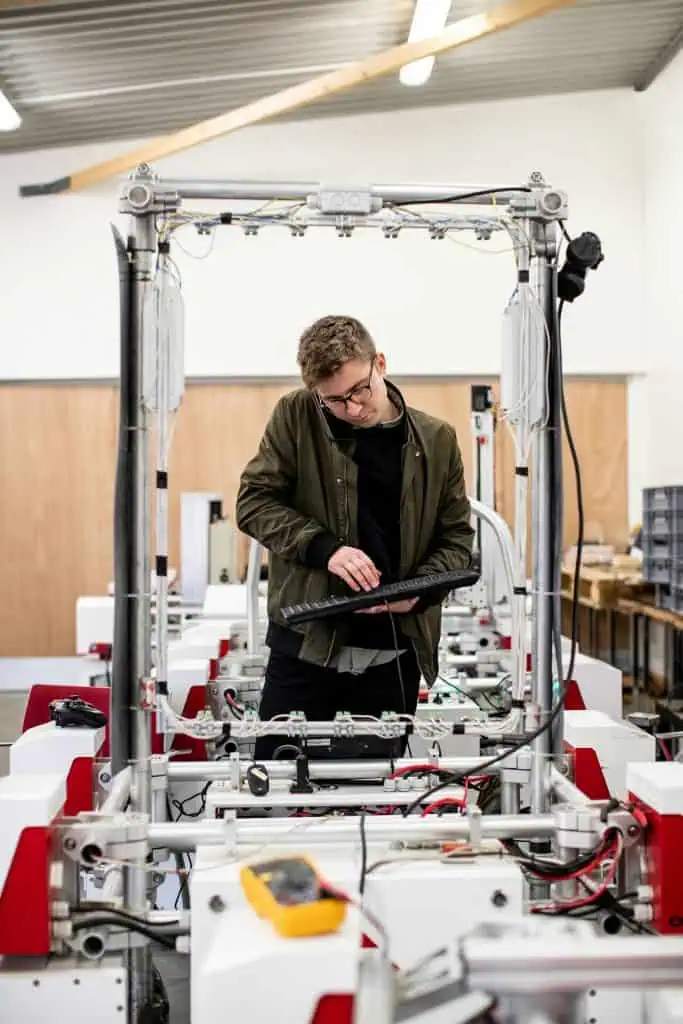 Automation engineer working on a machine while being on phone