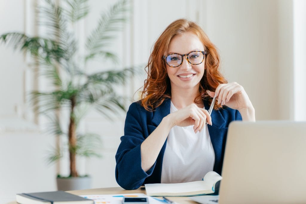 Smiling customer quality engineer sits at her desk in sunny office, working
